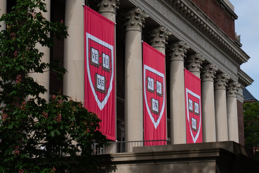 Red banners that say "Veritas" hang from a Harvard building in between columns.