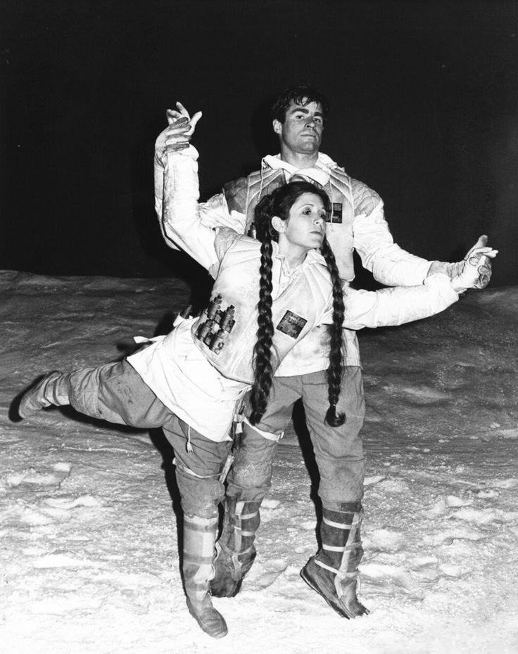 This may contain: two people dressed in costumes standing on snow covered ground with one holding the other's leg