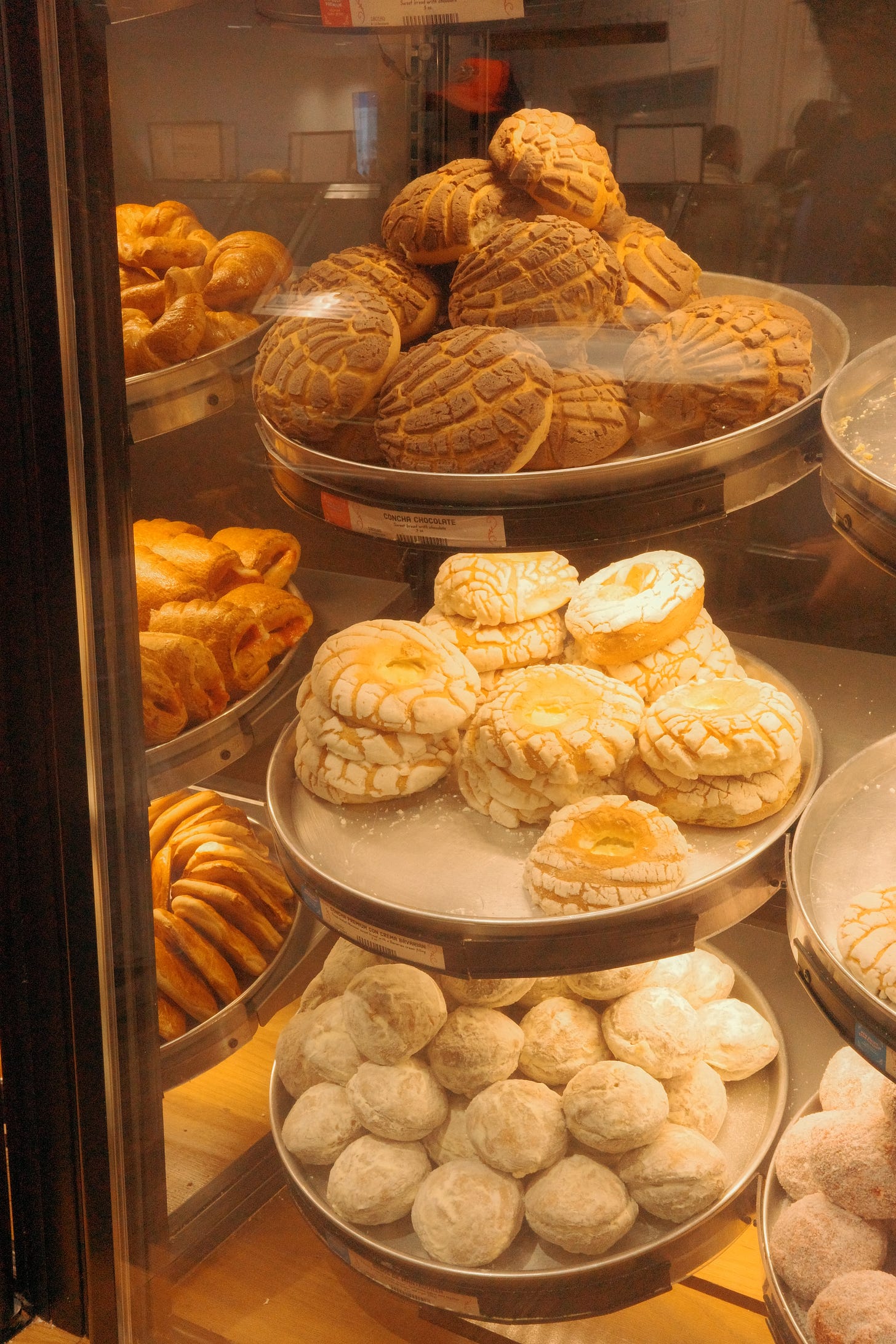 A pastry case filled with conchas and pastries.