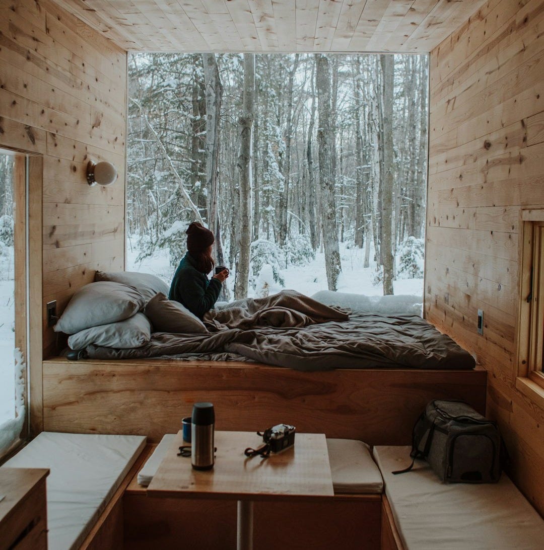 woman sitting on bed watching by the window during winter