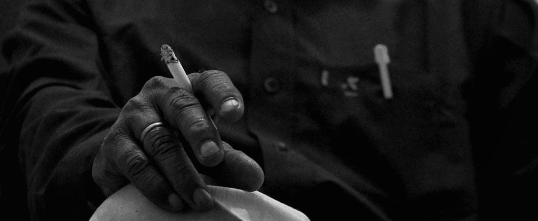 grayscale photo of man smoking cigarette