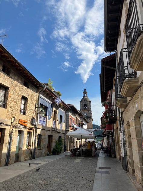 a high mountain path through greenery, roadside graffitti for Pays Basque independence, and a small Spanish town