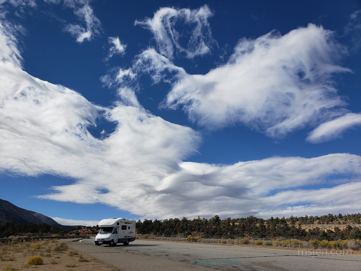 Wave style clouds blown ahead of a storm on the Eastern side of California's Sierra Nevada Mountains. A white RV motohome at a Vista stop in a dry Juniper grassland. Photo by Jenifer Hanen. 