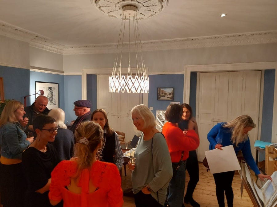 A room of people chatting and looking at pictures