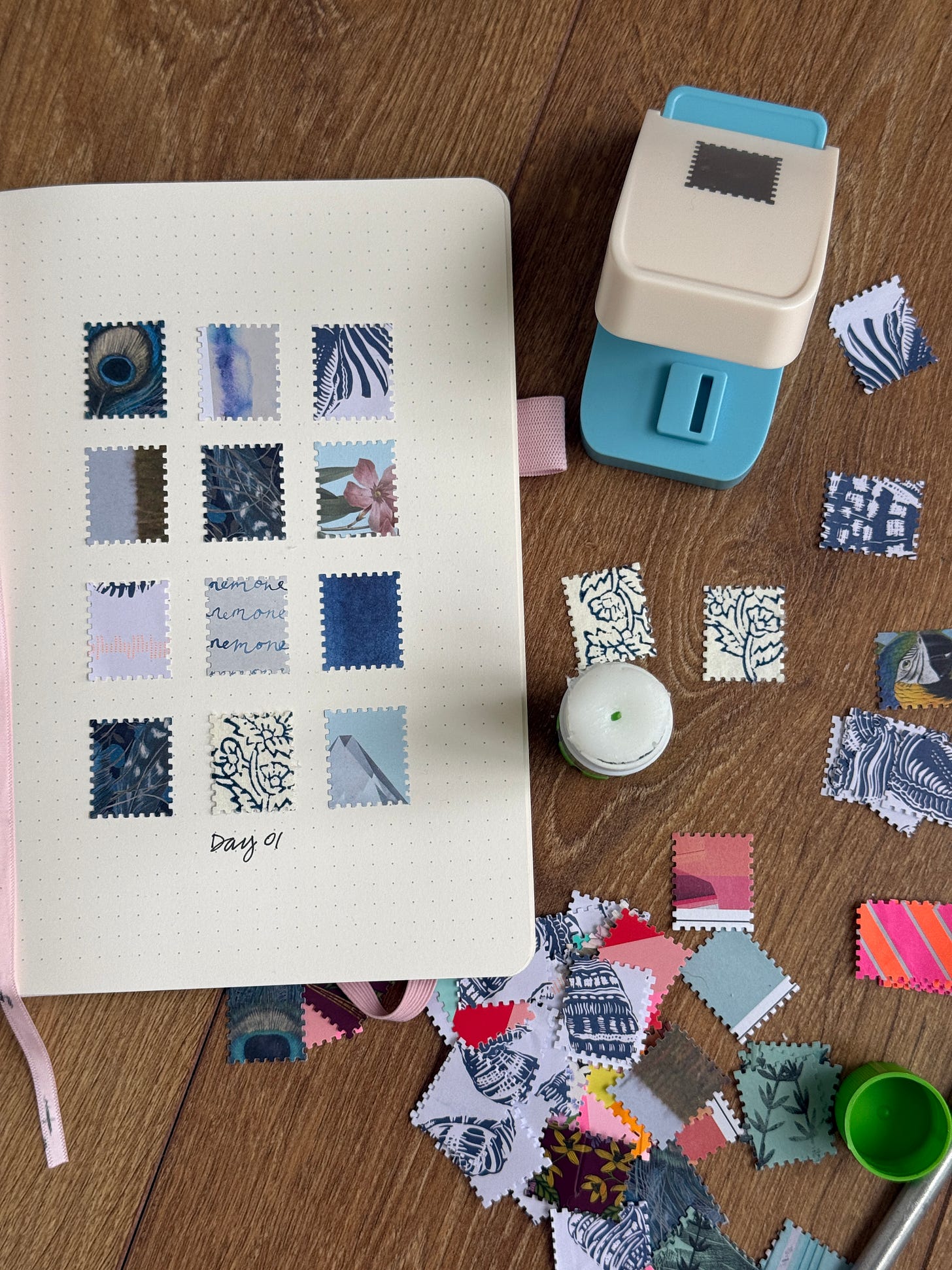 12 tiny squares cut from a stamp placed in a notebook with tiny stamps strewn across the table