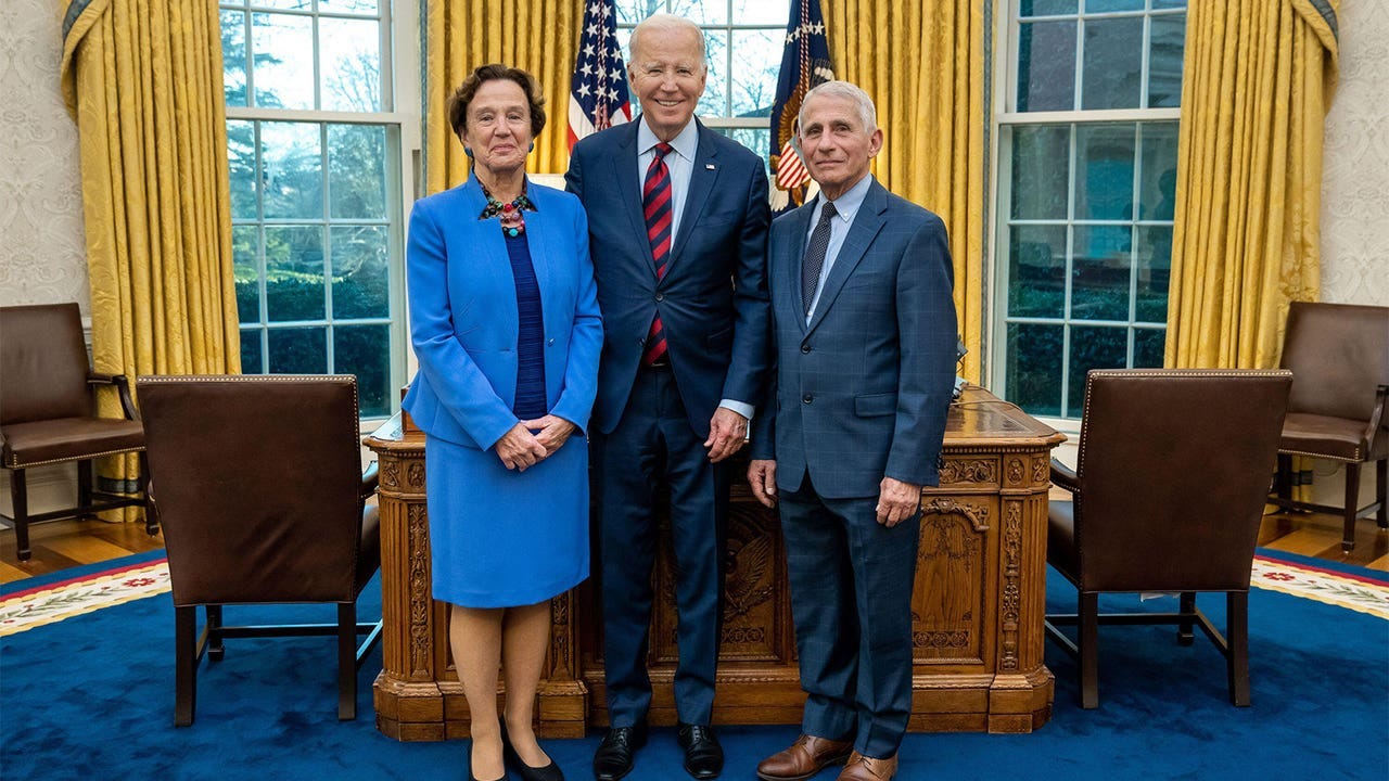 A photo of President Joe Biden, Dr. Anthony Fauci, and his wife Dr. Christine Grady in the Oval Office.