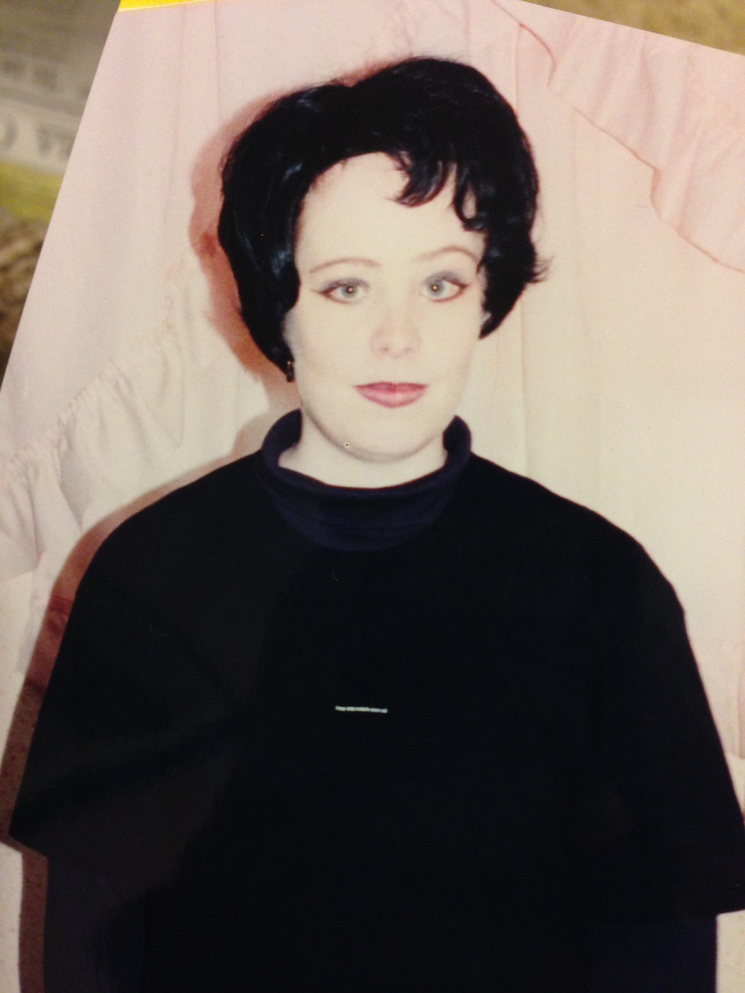 A white teenager in a black wig wearing black clothes and black eye liner