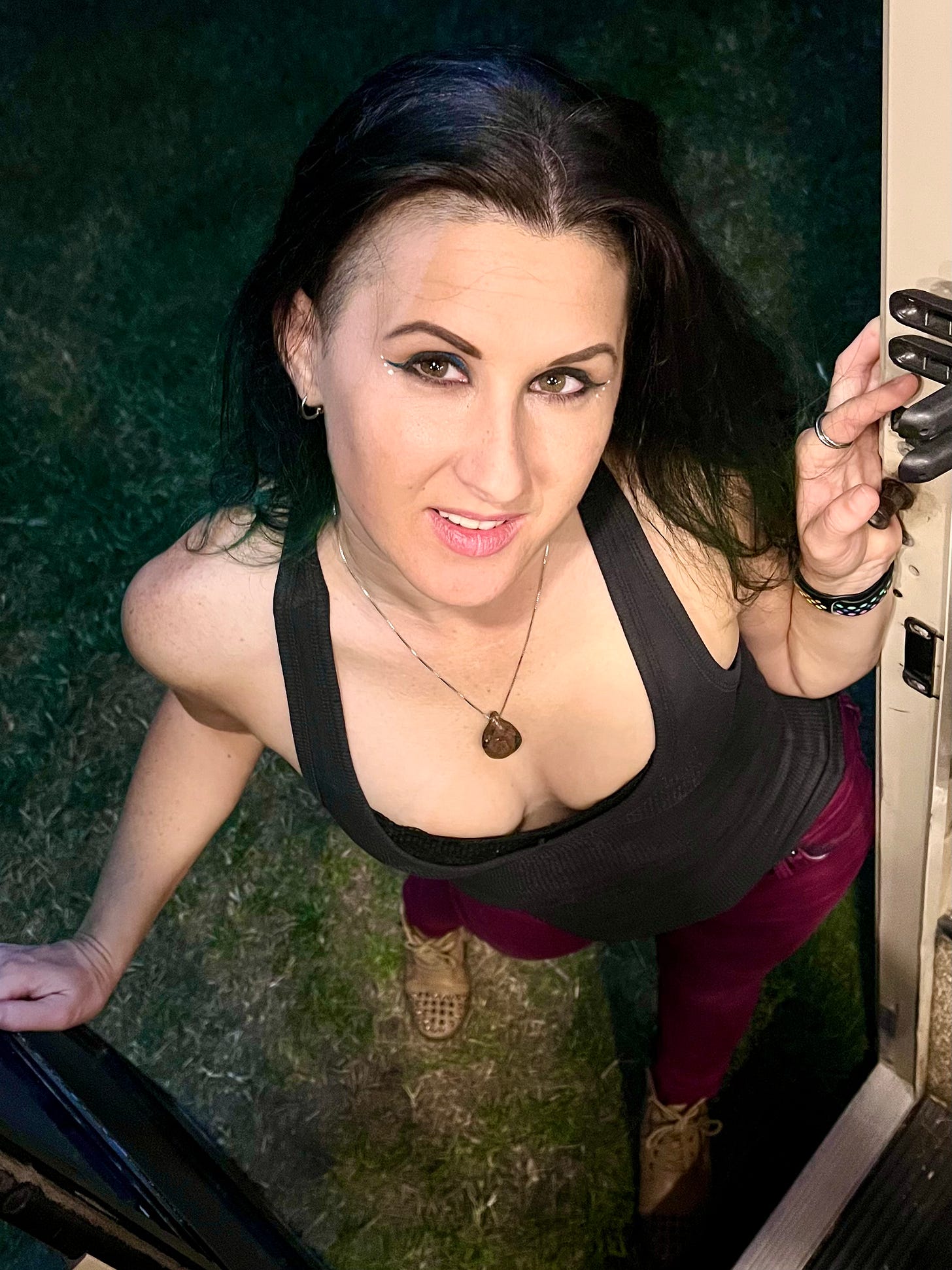 Lyric posing in the doorway of their RV, with red pants and a black shirt. 