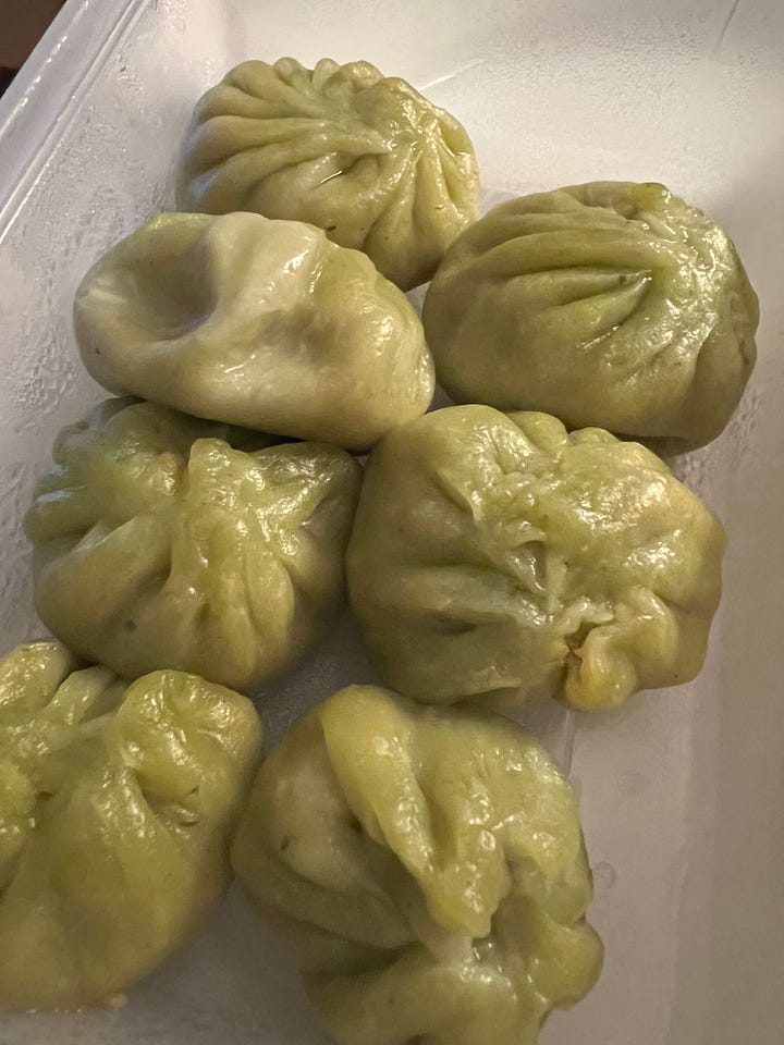 A dish of broken up samosas, topped with sauce, chickpeas, vermicelli, yoghurt & pomegranate seeds plus 3 dishes of different shaped filled dumplings, one with sauce