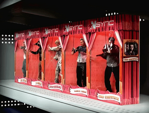 A shot from NSYNC's "No Strings Attached" music video where the band members are fighting their way out of the doll boxes they're trapped in.