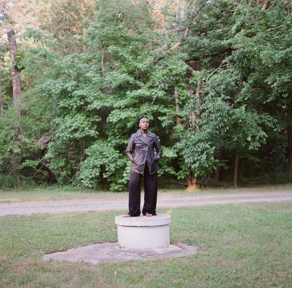 In 2021, I shaved my head months before answering the invitation to move to land that has been in my family for five generations. This photo was taken while standing on a well that was in the front yard of the family owned home I moved into in order to write Cykofa: The Seeda Origin Story in Dawn, Virginia — tucked in between the ancestral lands of the Mattaponi and Youghtanund. Photography by: Chukwudumebi Ezefili