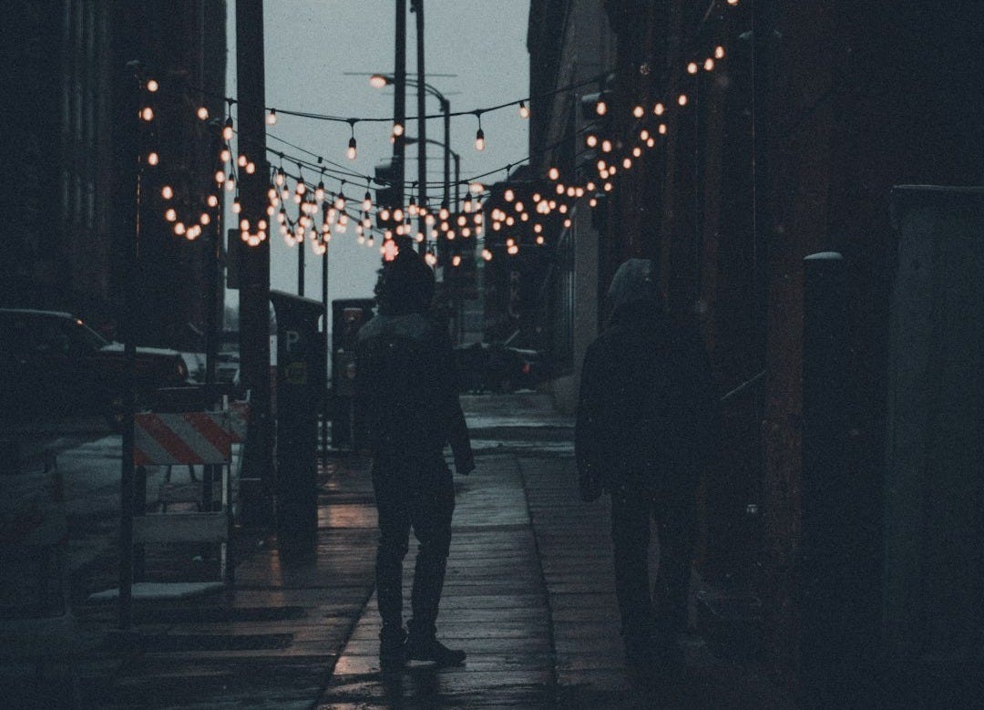 silhouette of people walking on sidewalk during night time