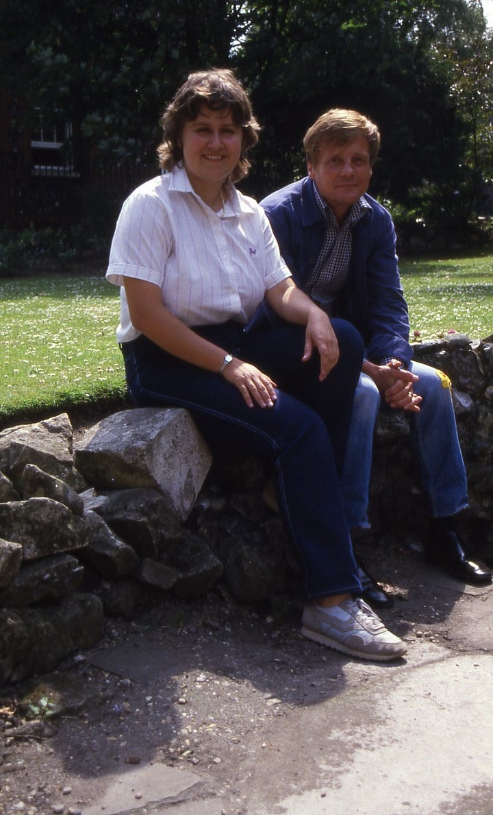 Serious young man head and shoulders, woman and man sitting onstone wall