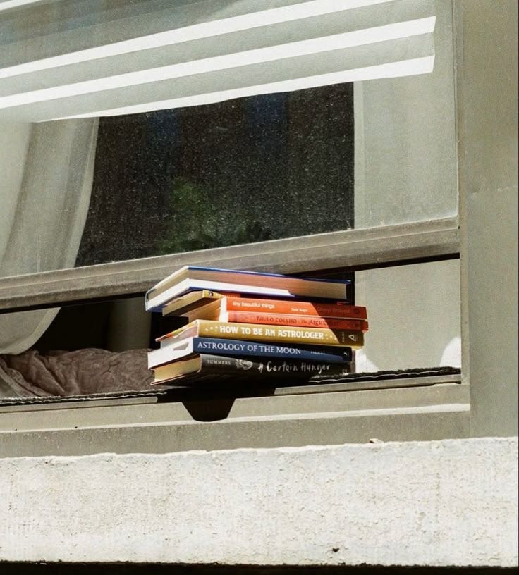 This may contain: a stack of books sitting on top of a window sill This may contain: a stack of books sitting on top of a window sill