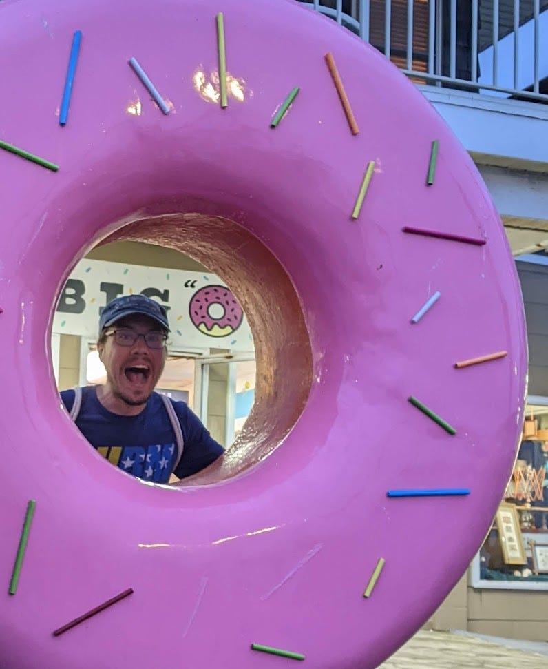 Me looking through the hole of a giant pink donut