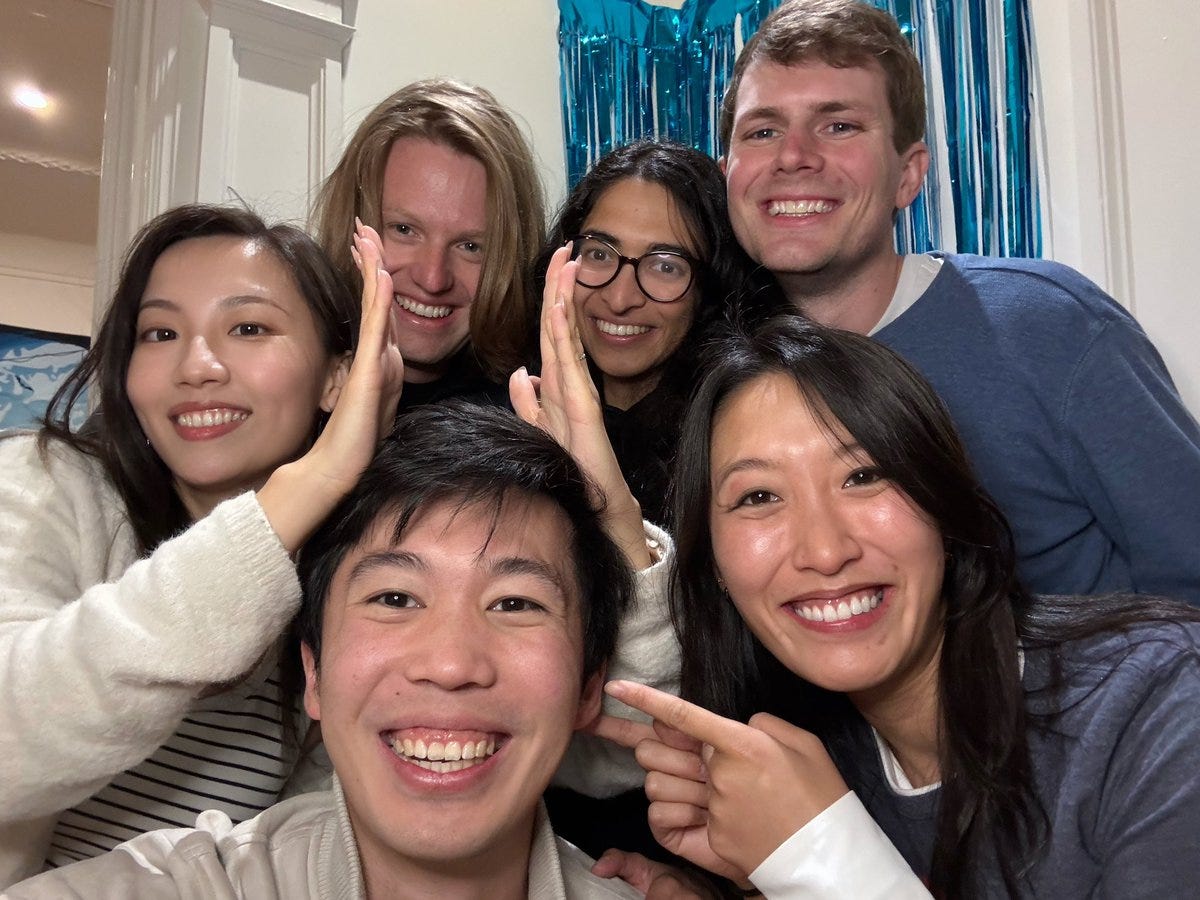 A diverse group of friends smiling together with a blue backdrop.