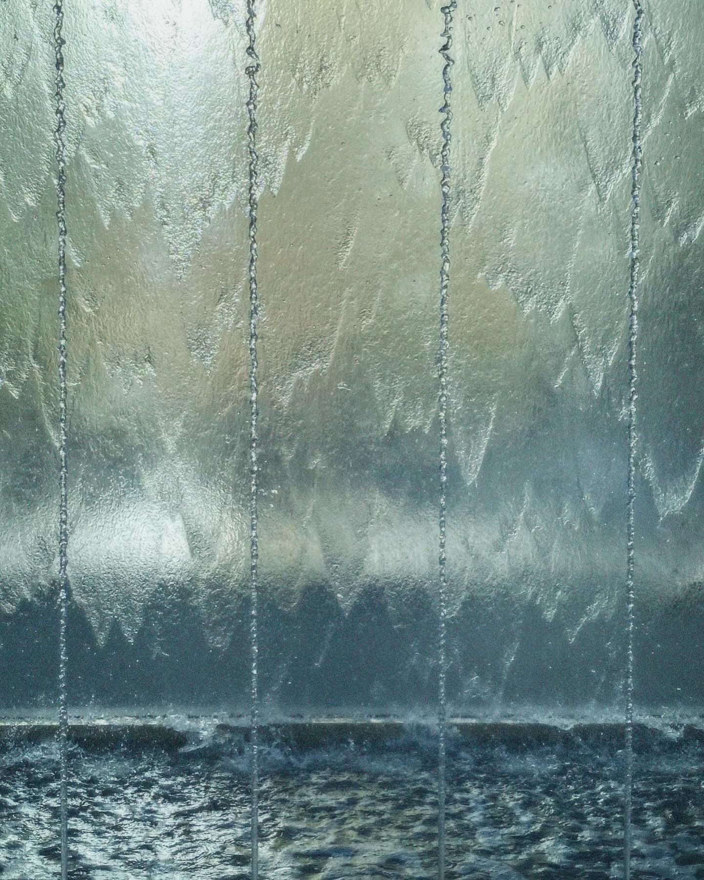 A close shot of the cascading water entrance to Apple Piazza Liberty in Milan. Waves of water slide down the glass creating a mesmerizing effect.