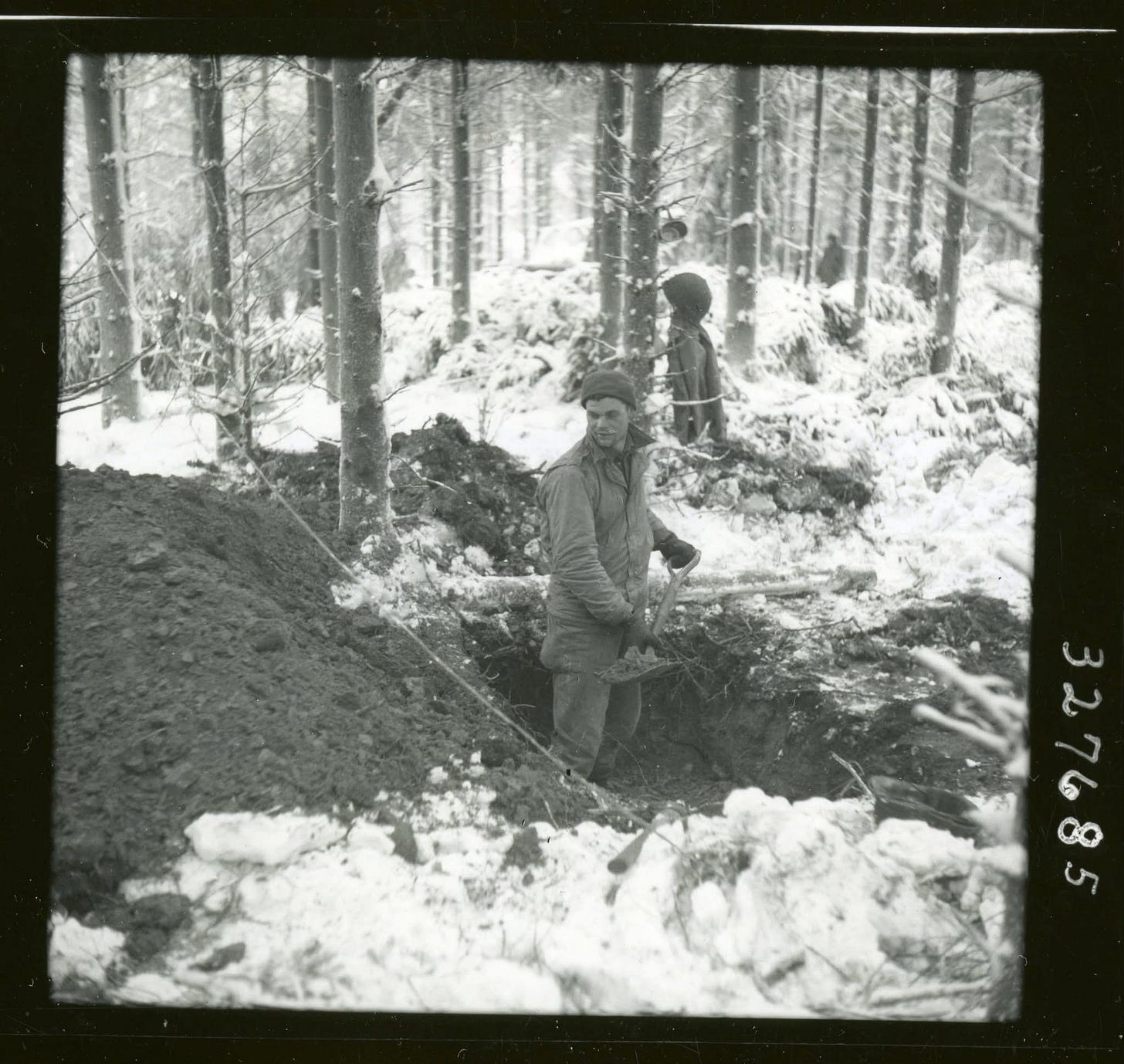 Cpl. Roy Jordan endures the brutal cold, digging in for the night in the frozen Ardennes Forest during the Battle of the Bulge, December 1944.