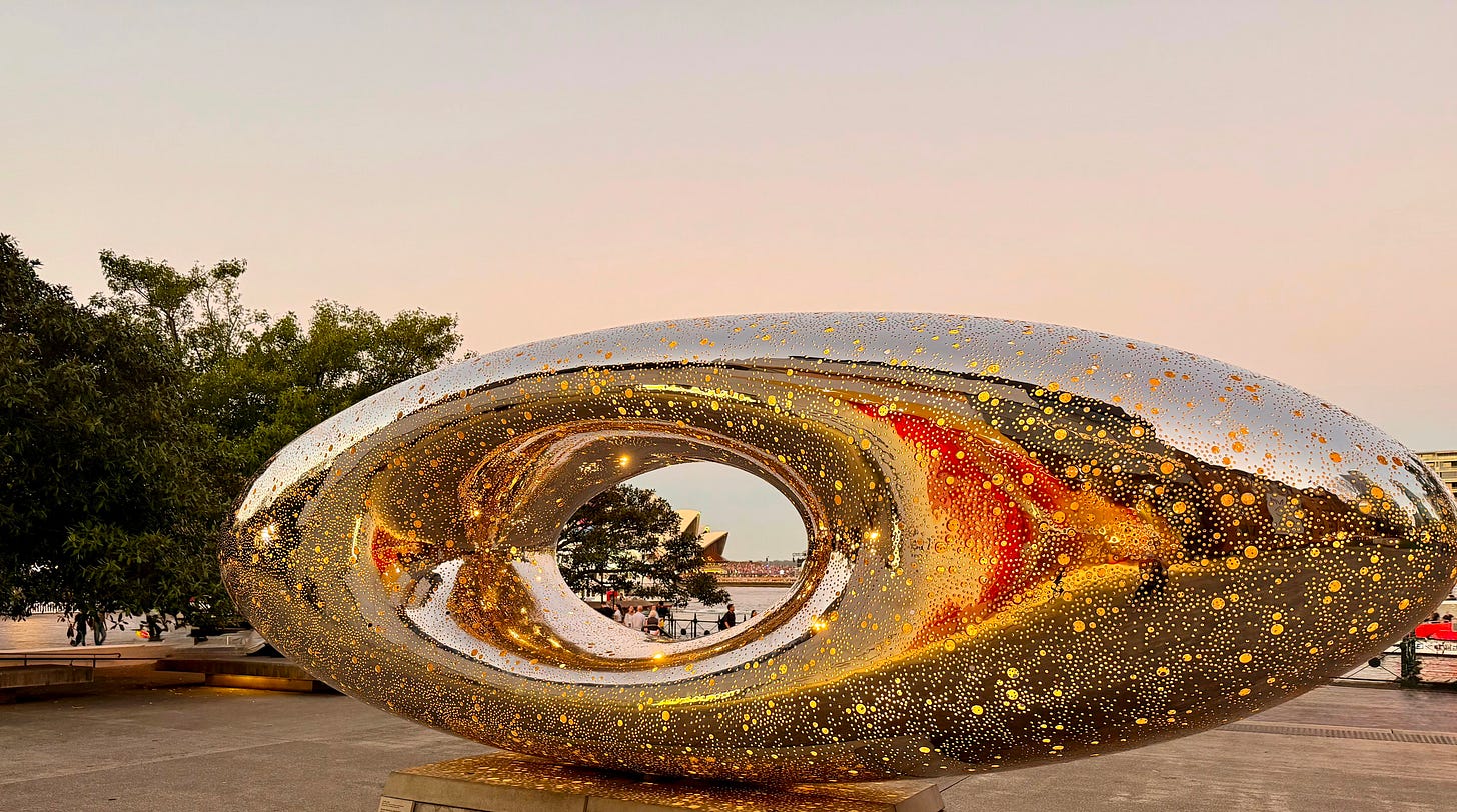 Reflective gold sculpture outside the Museum of Contemporary Art in Sydney with harbor in the background. Reflective gold sculpture outside the Museum of Contemporary Art in Sydney with harbor in the background.
