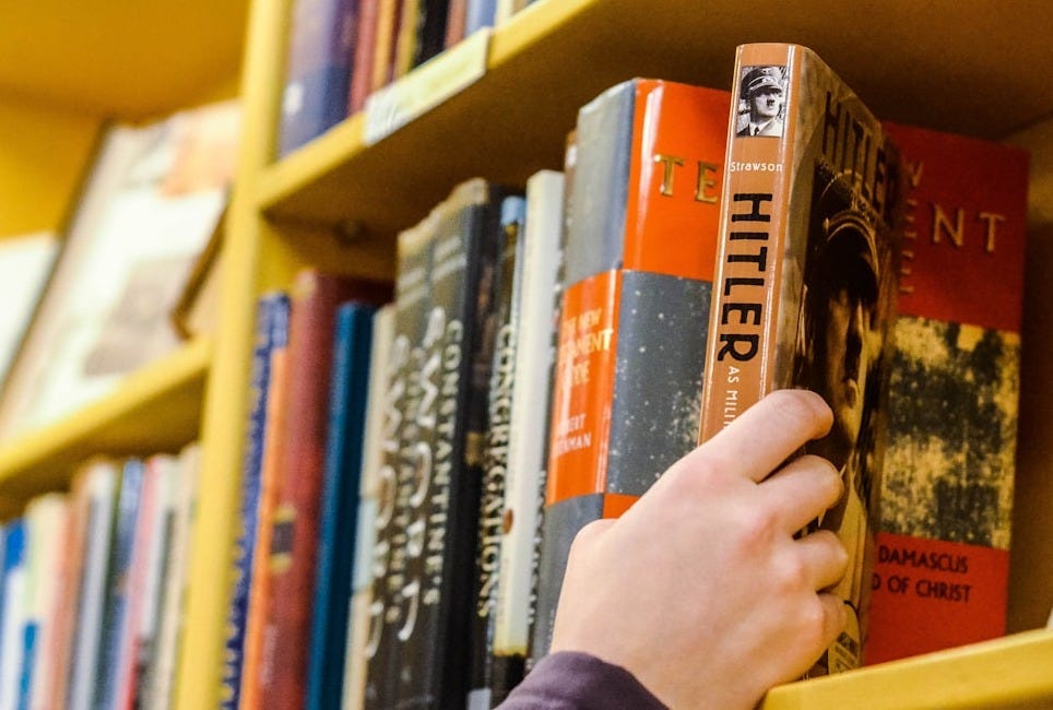 person holding book in book shelf