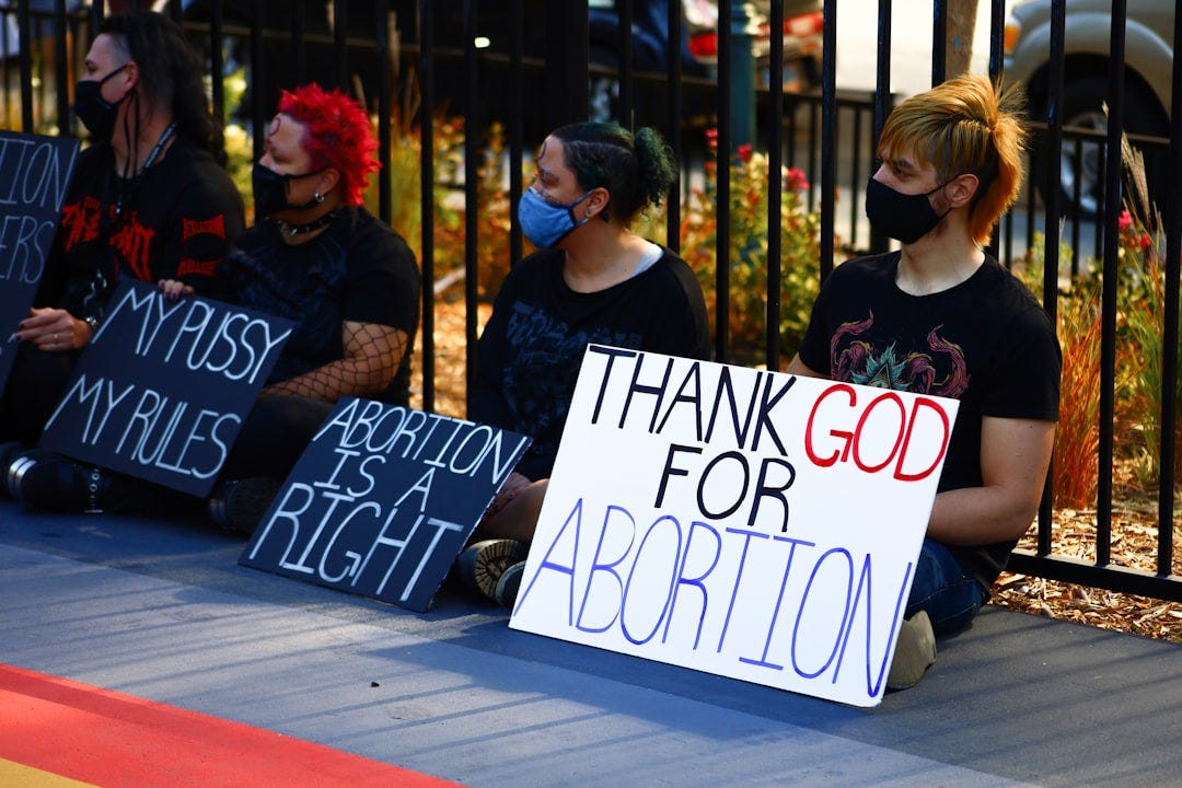 a group of people sitting next to each other holding signs a group of people sitting next to each other holding signs