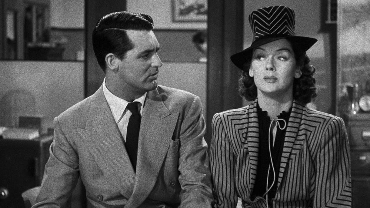 Cary Grant looks sideways at Rosalind Russell in a very fancy hat in His Girl Friday