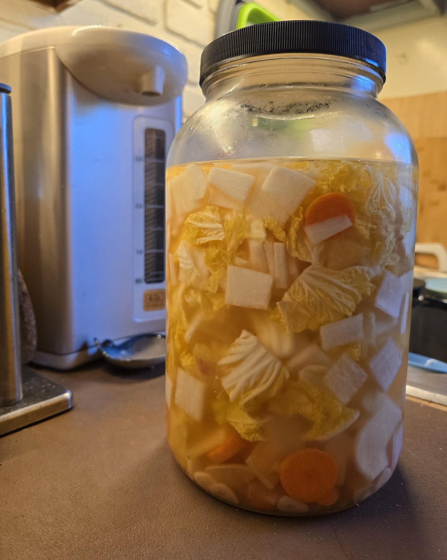 A gallon glass jar of water kimchi sits on my kitchen counter.