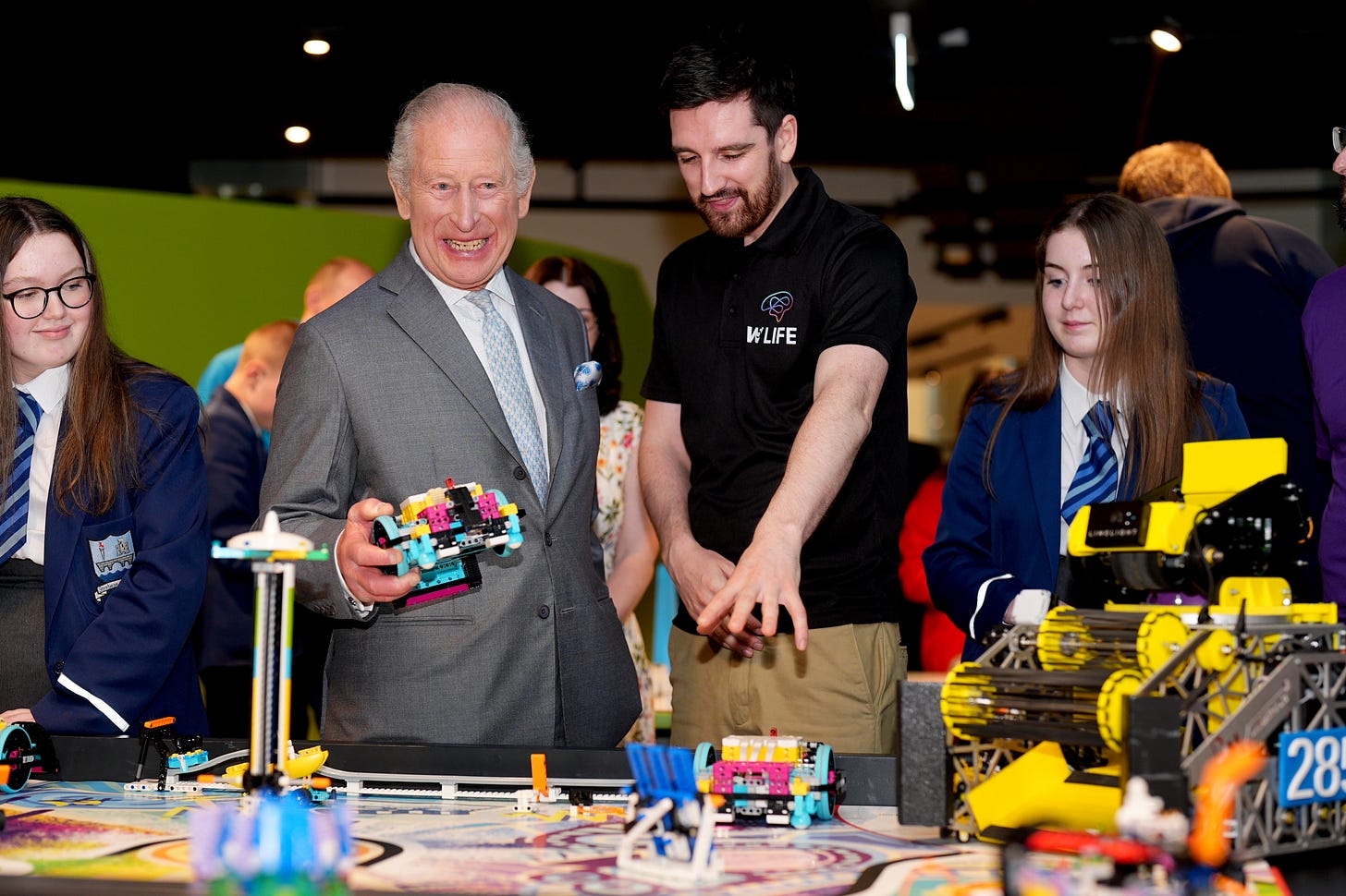 King Charles smiling and holding a lego robot