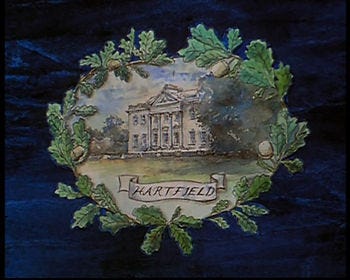 A painting of a Georgian mansion labeled Hartfield and surrounded by a leaf wreath on dark blue background.