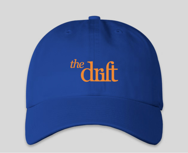 A blue cap with The Drift logo on the front in orange text. A blue cap with The Drift logo on the front in orange text.
