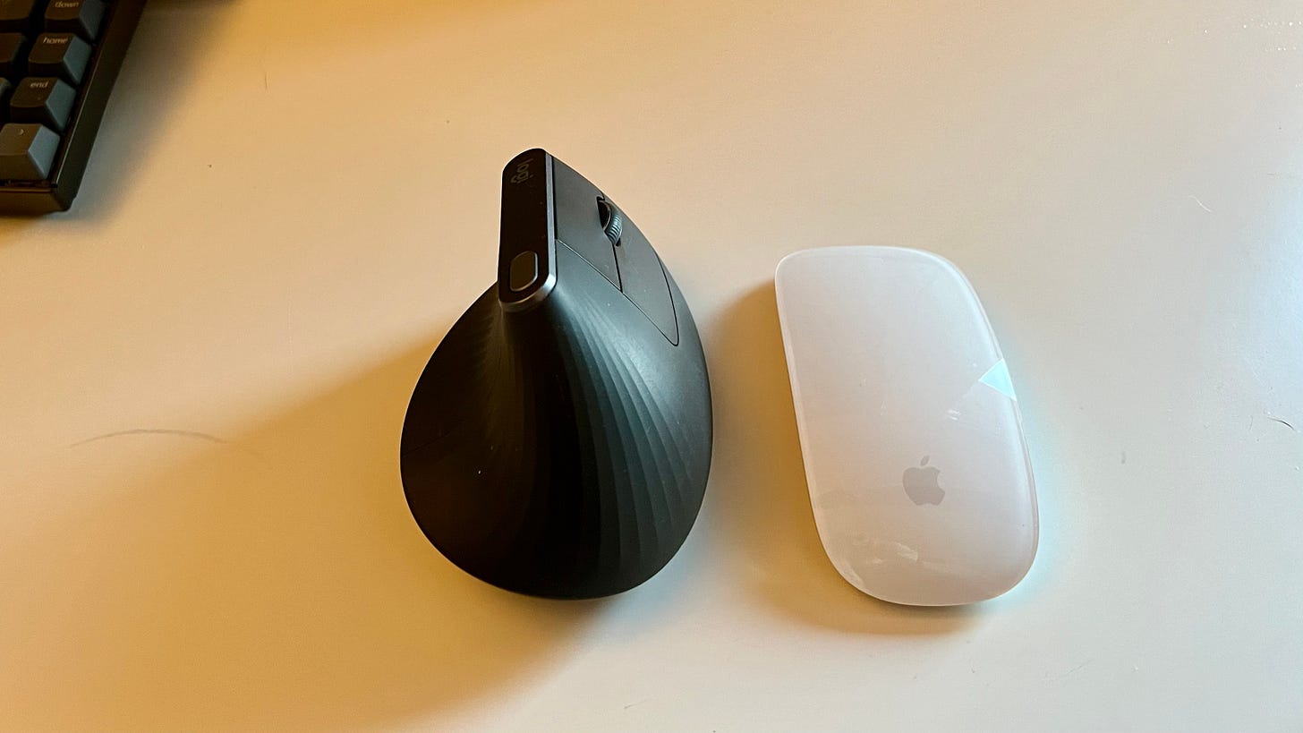 The Logitech MX Vertical next to the Magic Mouse. 
