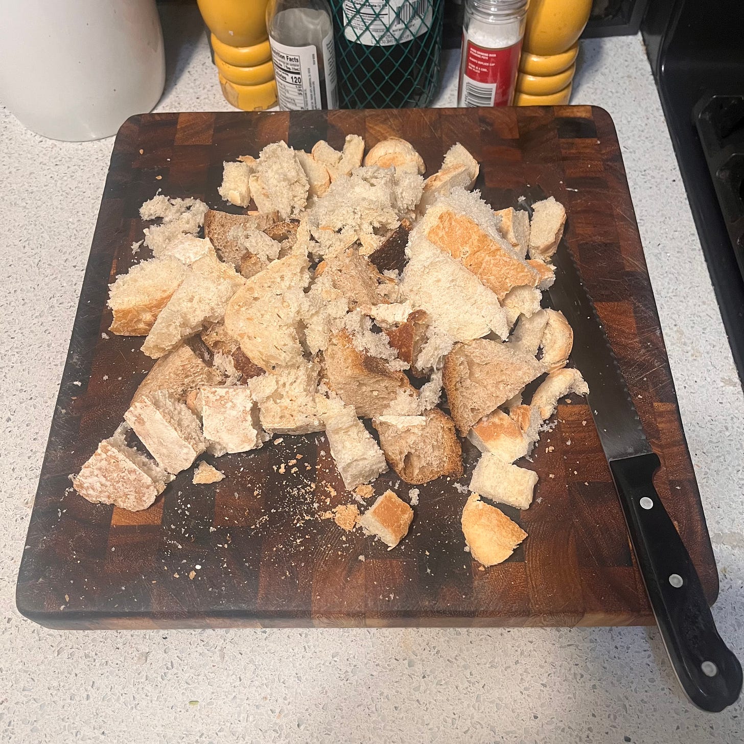 a wooden cutting board with a variety of bread chunks and a bread knife on a kitchen table a wooden cutting board with a variety of bread chunks and a bread knife on a kitchen table