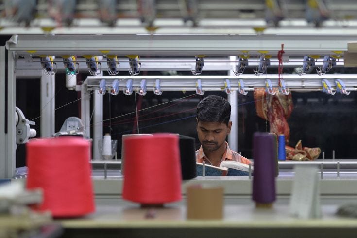 This may contain: a man working in a factory with red and purple spools on the line