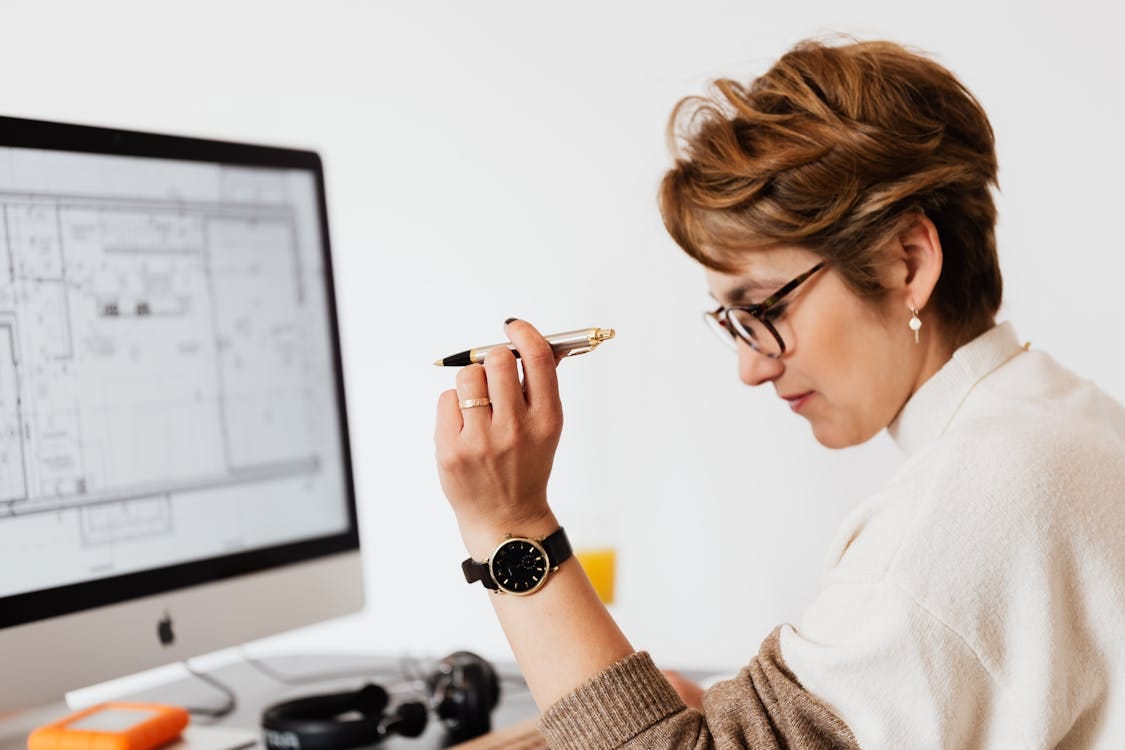 Free Confident businesswoman using computer for architectural analysis in a modern office. Stock Photo