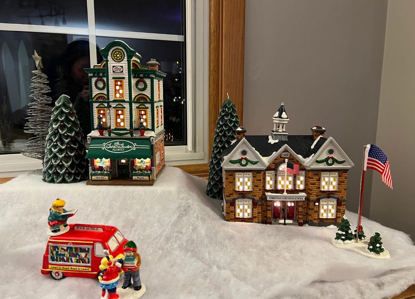 Three pieces of a snow village rest on a piece of white felt. 
