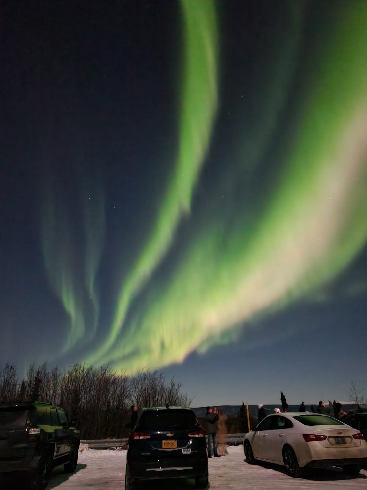 Green aurora over a snowy parking lot