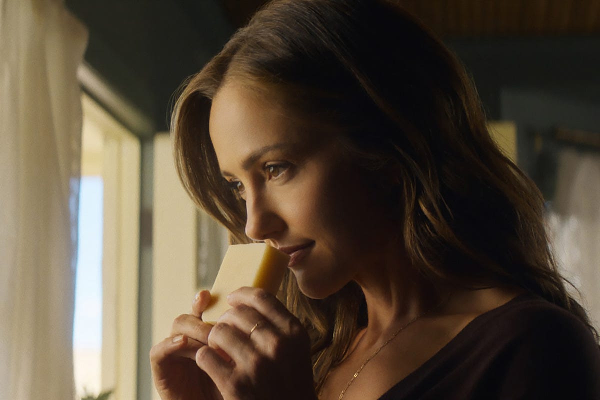 Quinn smells soap while standing in front of the window.