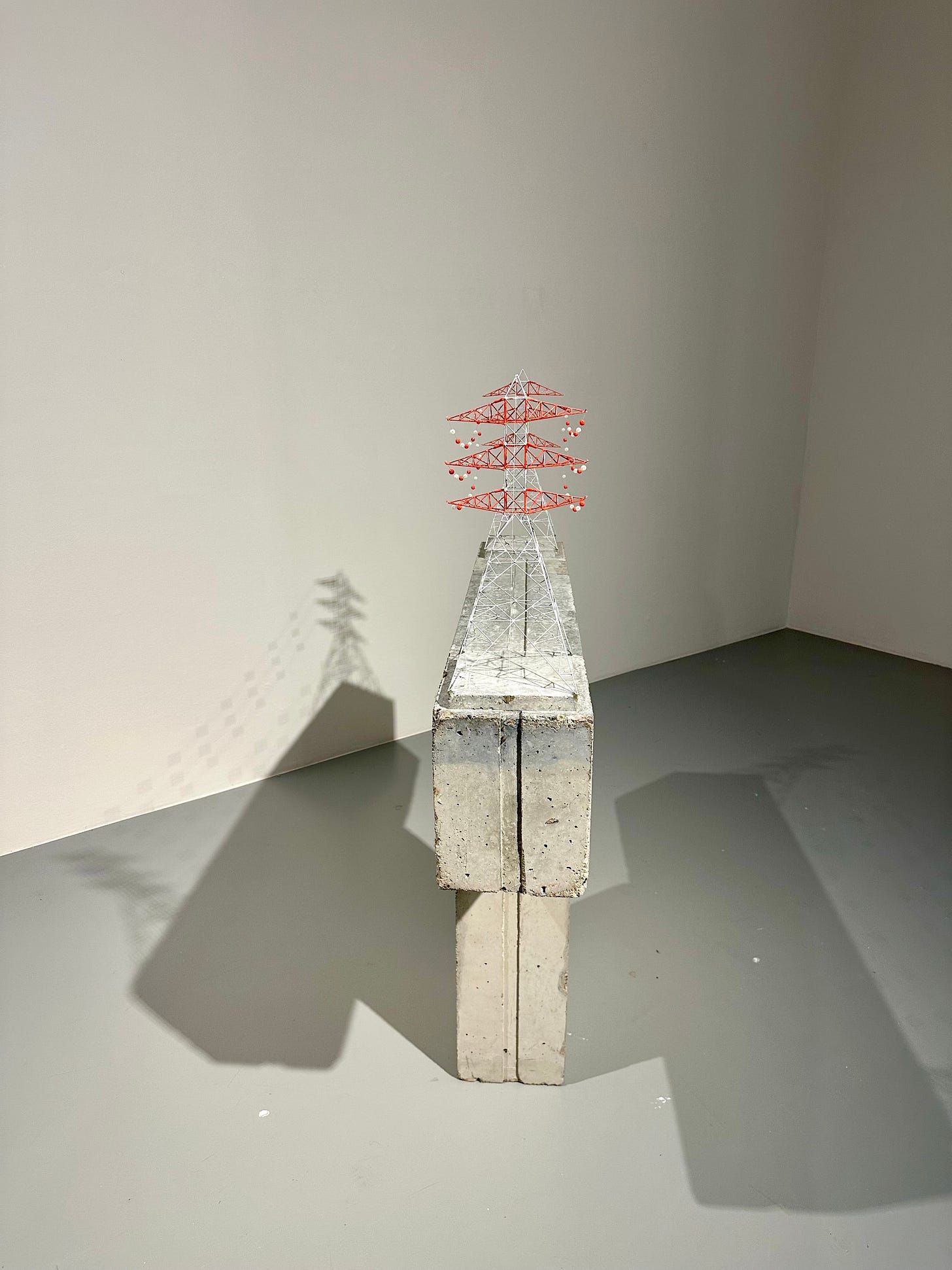 A concrete and wire sculpture in a gallery that, from my heightened perspective, casts a shadow which in appear to resemble "M".