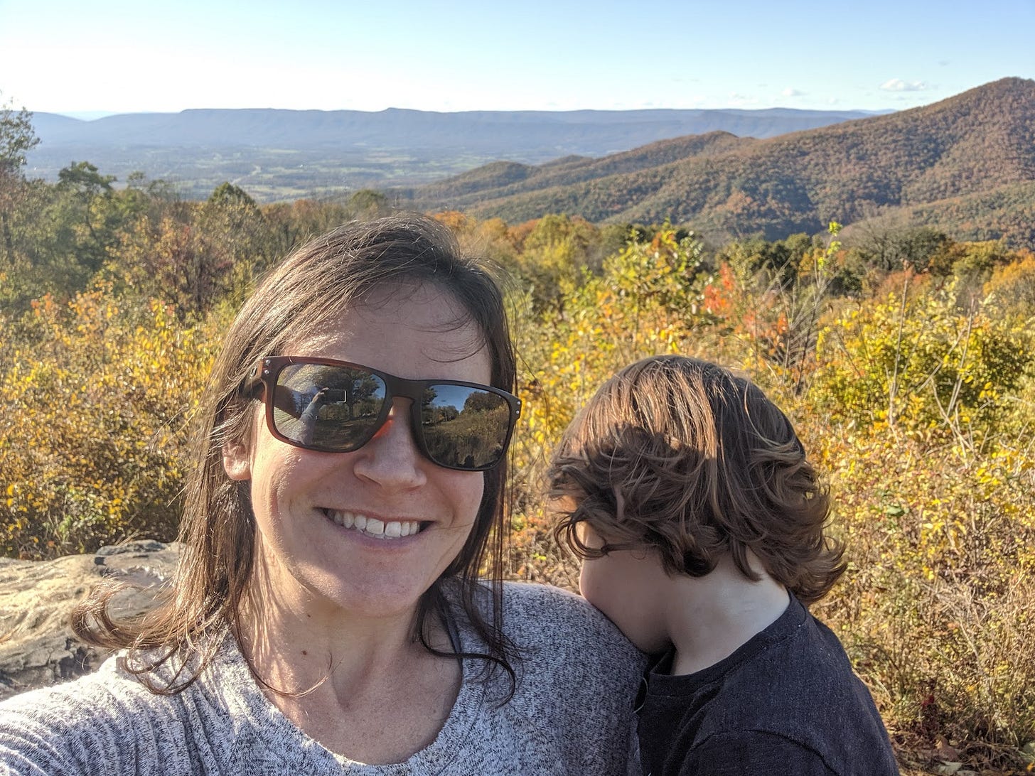 Shannon holding her son, who is looking away, with a fall mountain scenery backdrop.