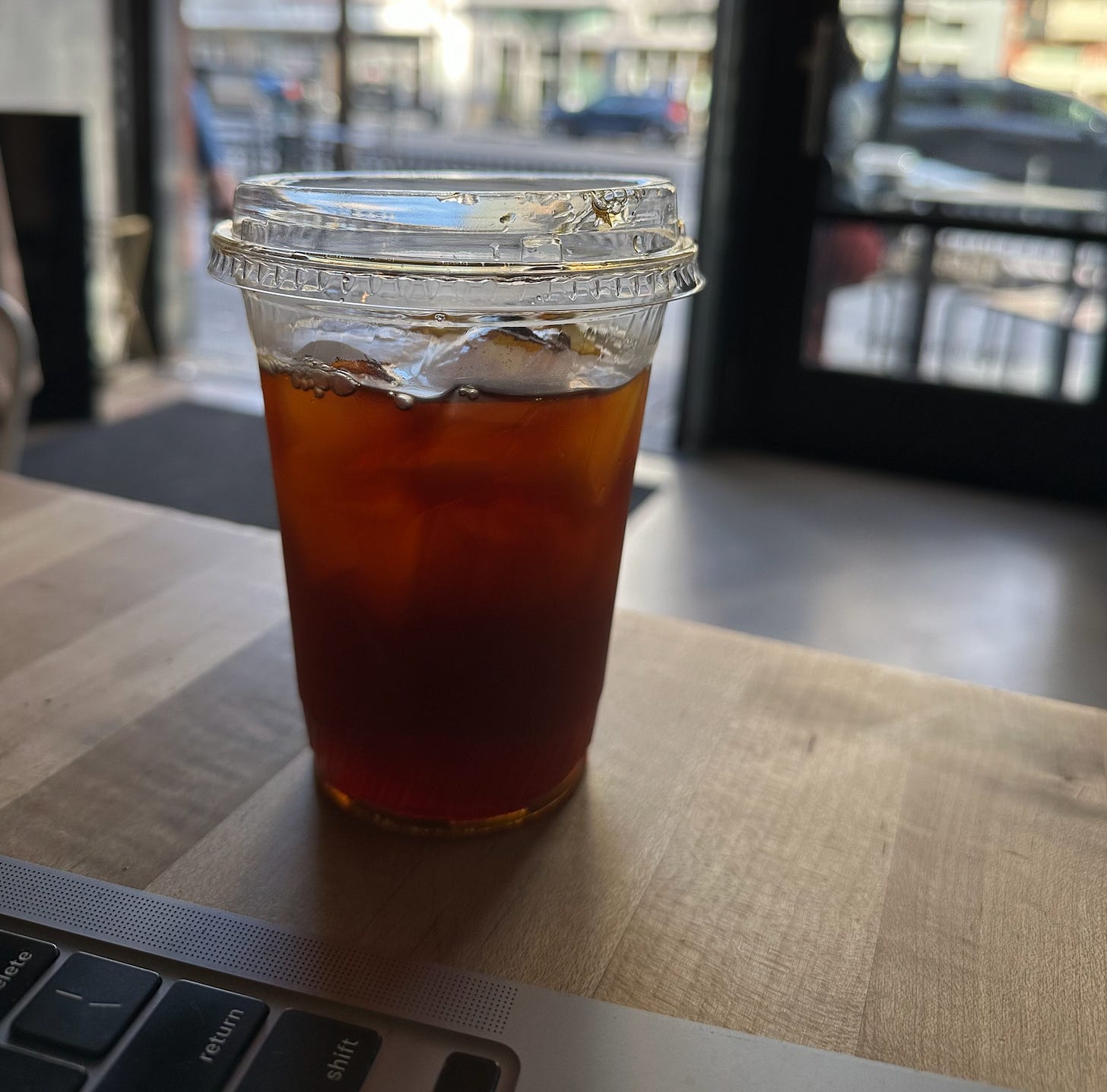 Chris's iced coffee sits on a table beside his laptop.
