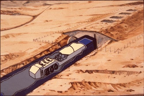 A box labeled “MX MISSILE” holds numerous watercolor illustrations of a southwestern desert landscape beneath smoldering purple sky, the terrain punctuated by ICBM storage bunkers. If you can ignore the fact that each of these bumps contains radioactive death, they look like paintings from a doctor’s waiting room or a beach rental. The MX, later known as the Peacekeeper, was an ICBM designed to simultaneously rain down on its target—Russia—ten separate nuclear warheads over ten times as powerful as the one that destroyed Nagasaki.