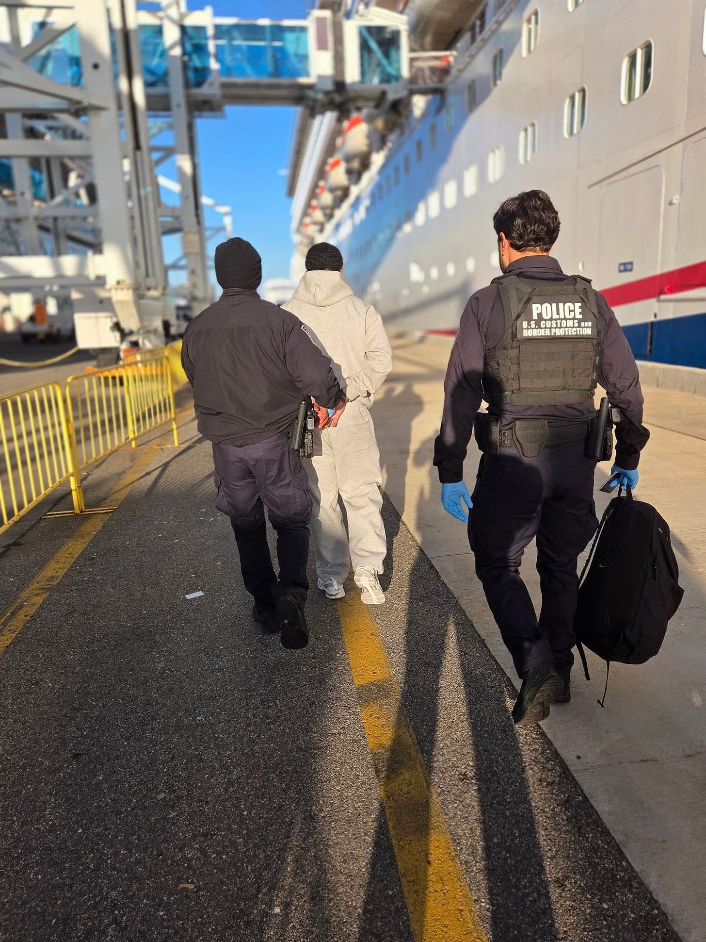 US Customs & Border Protection officers escort a passenger arrested on a Florida cruise ship for an out-of-state warrant. (CBP photo) US Customs & Border Protection officers escort a passenger arrested on a Florida cruise ship for an out-of-state warrant. (CBP photo)