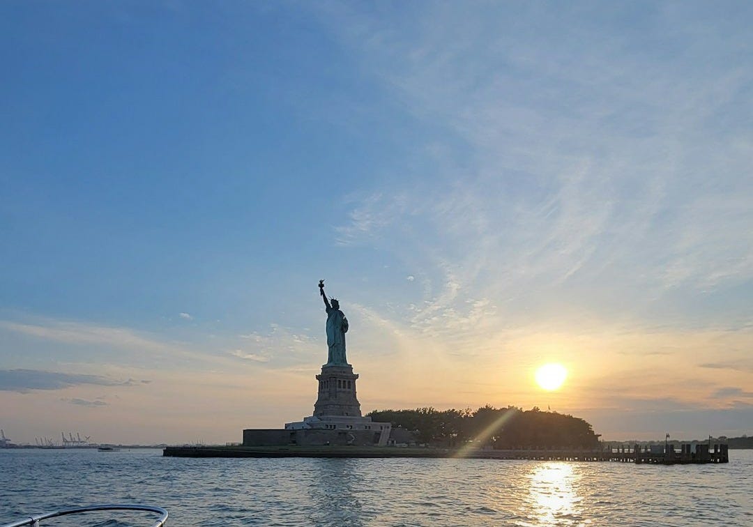 a statue on a boat in the water with a sunset in the background a statue on a boat in the water with a sunset in the background
