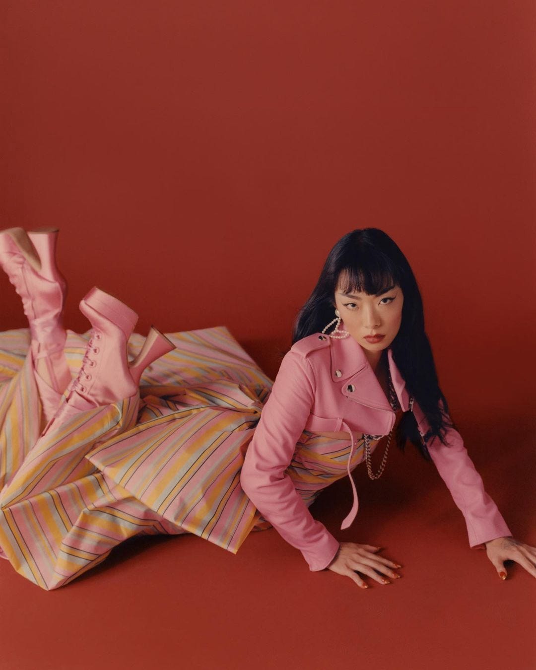 Rina Sawayama posing in front of a red background