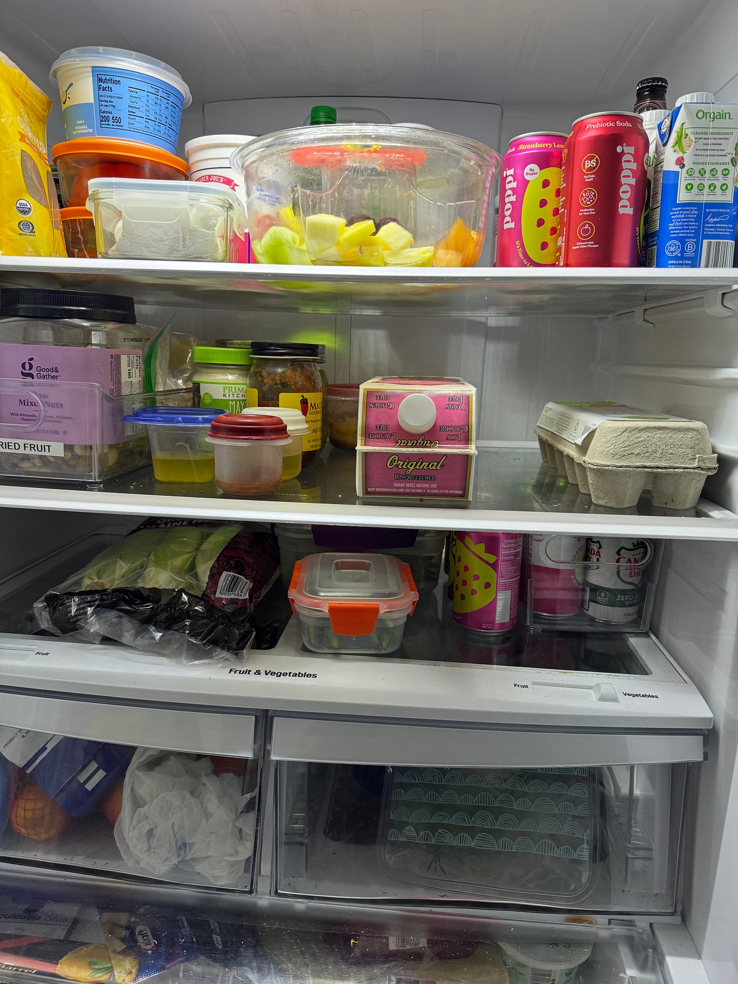 An open refrigerator with a carton of almond milk in the middle of the second shelf