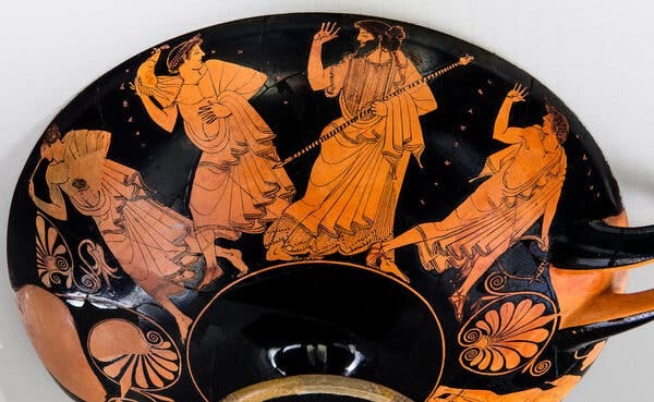 An exterior view of the kylix that was formerly on display at the Met shows older men pursuing younger ones. The painted figures are dressed in robe-like garments and can be seen holding a variety of everyday objects and gifts.