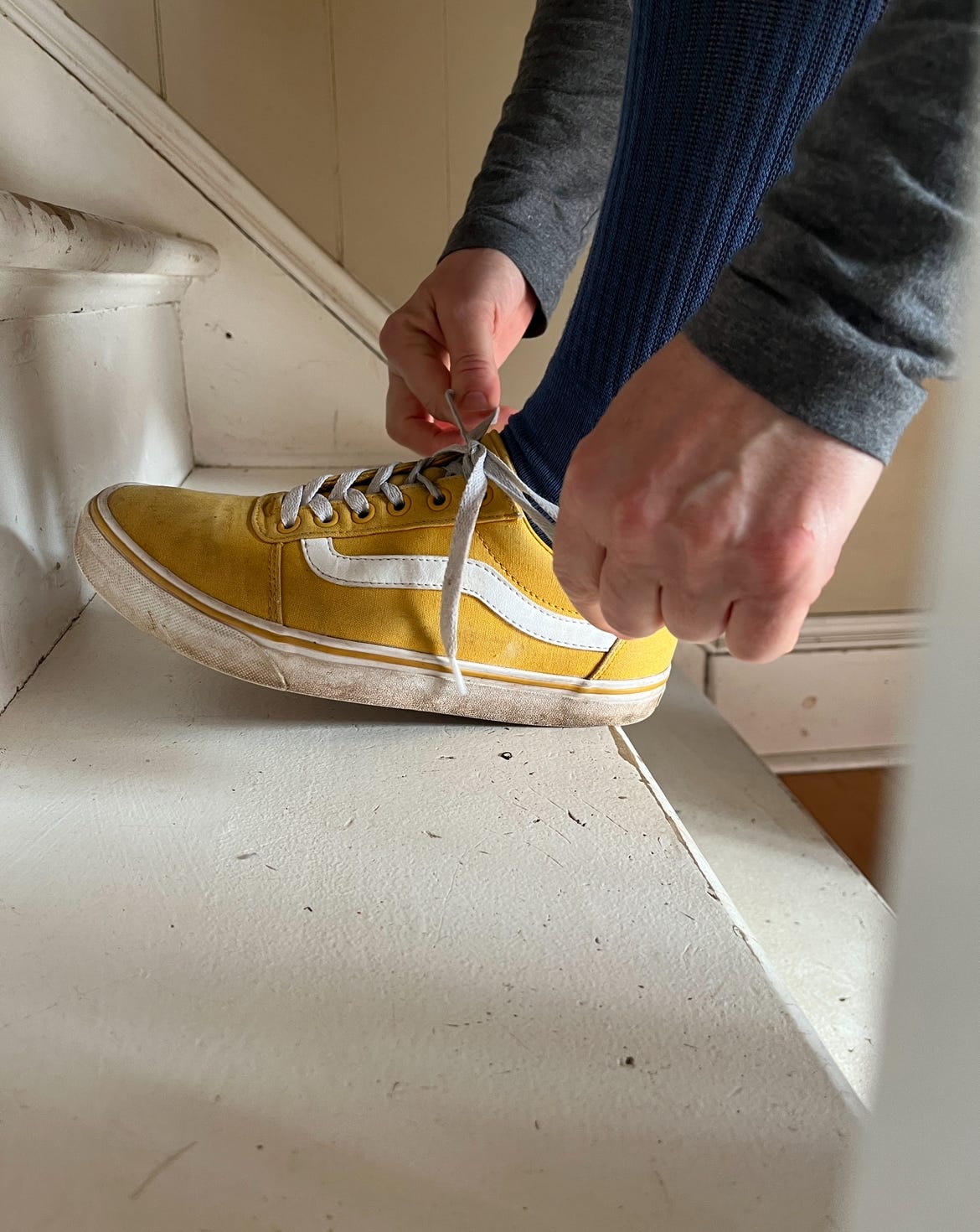 Erin tying her bright yellow running shoes on the white stairs