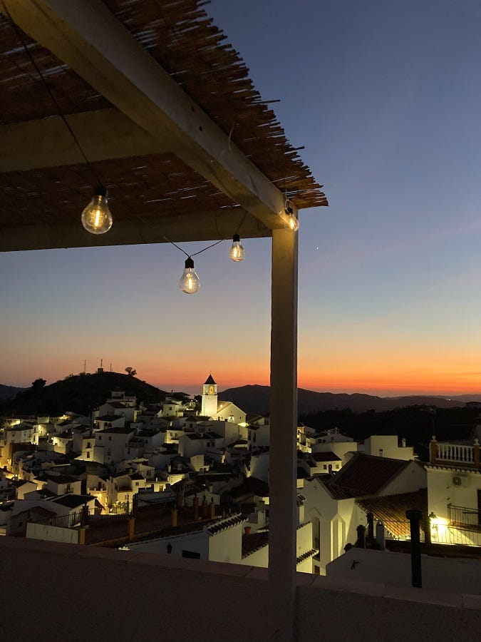 Spain Casa Cubista Local Hideaways Dämmerung mit Blick über die kleine, weiße, pittoreske Stadt, der gleiche Blick wie zuvor, nur noch etwas dunkler, eine Lichterkette und beleuchtete Häuser, gemütliche Atmosphäre