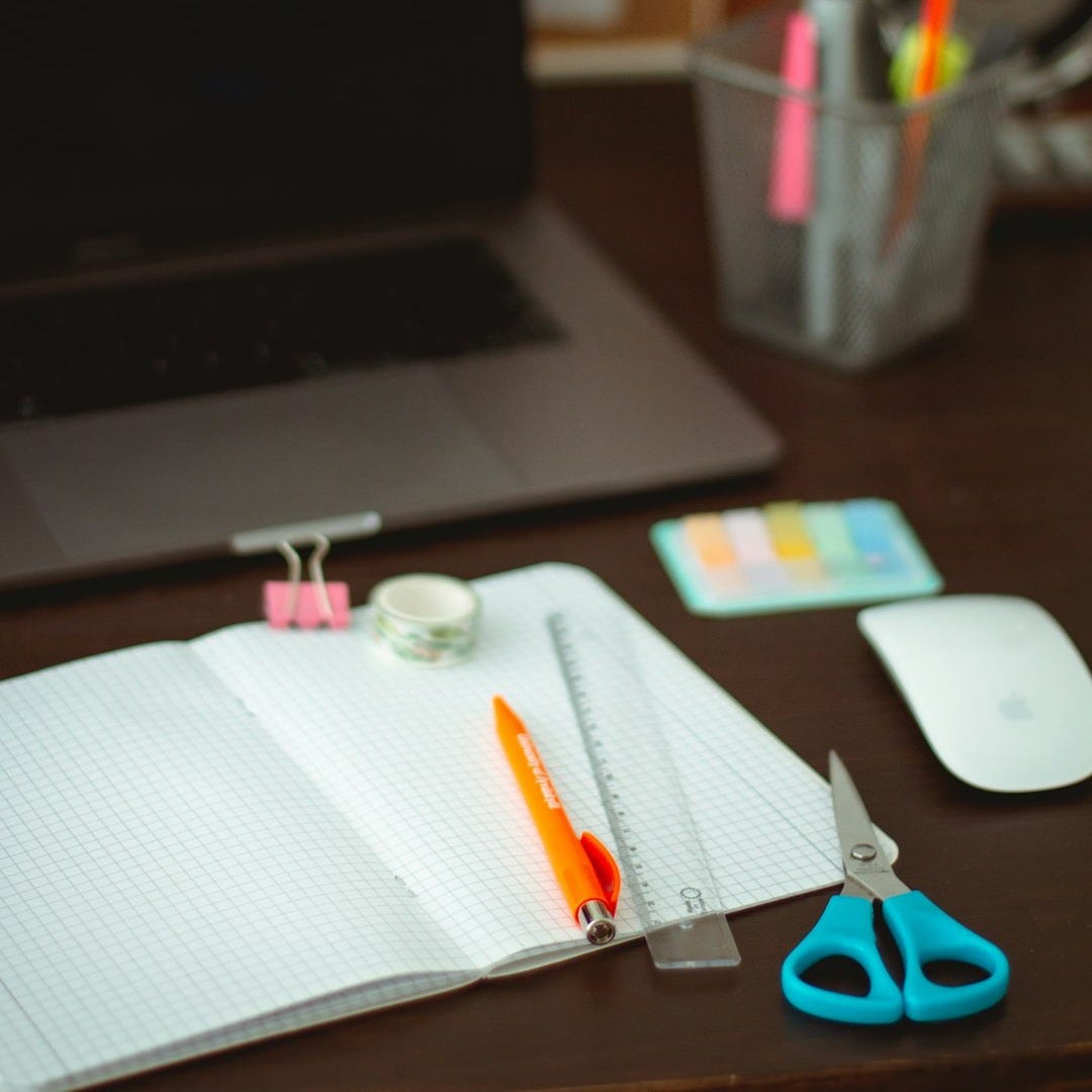 black and silver laptop computer beside white printer paper on brown wooden table