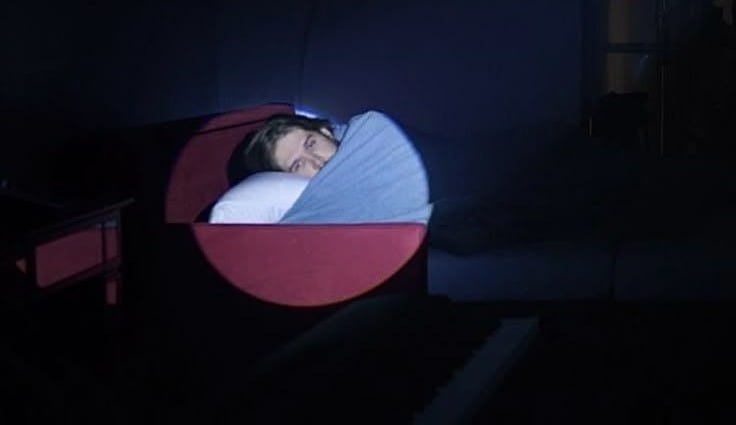 This may contain: a person sleeping in a bed with a blue and red circle on it's side